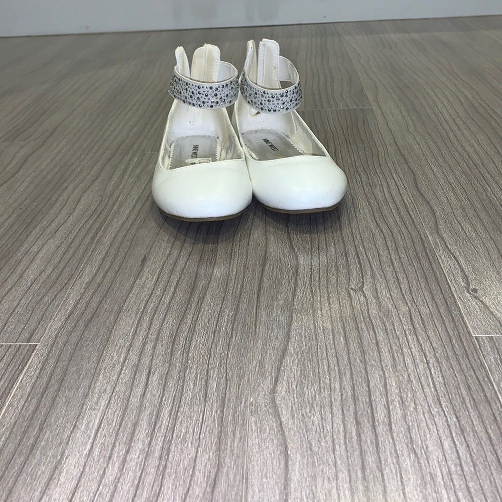 White Nine West flats with strap around the ankle and gems